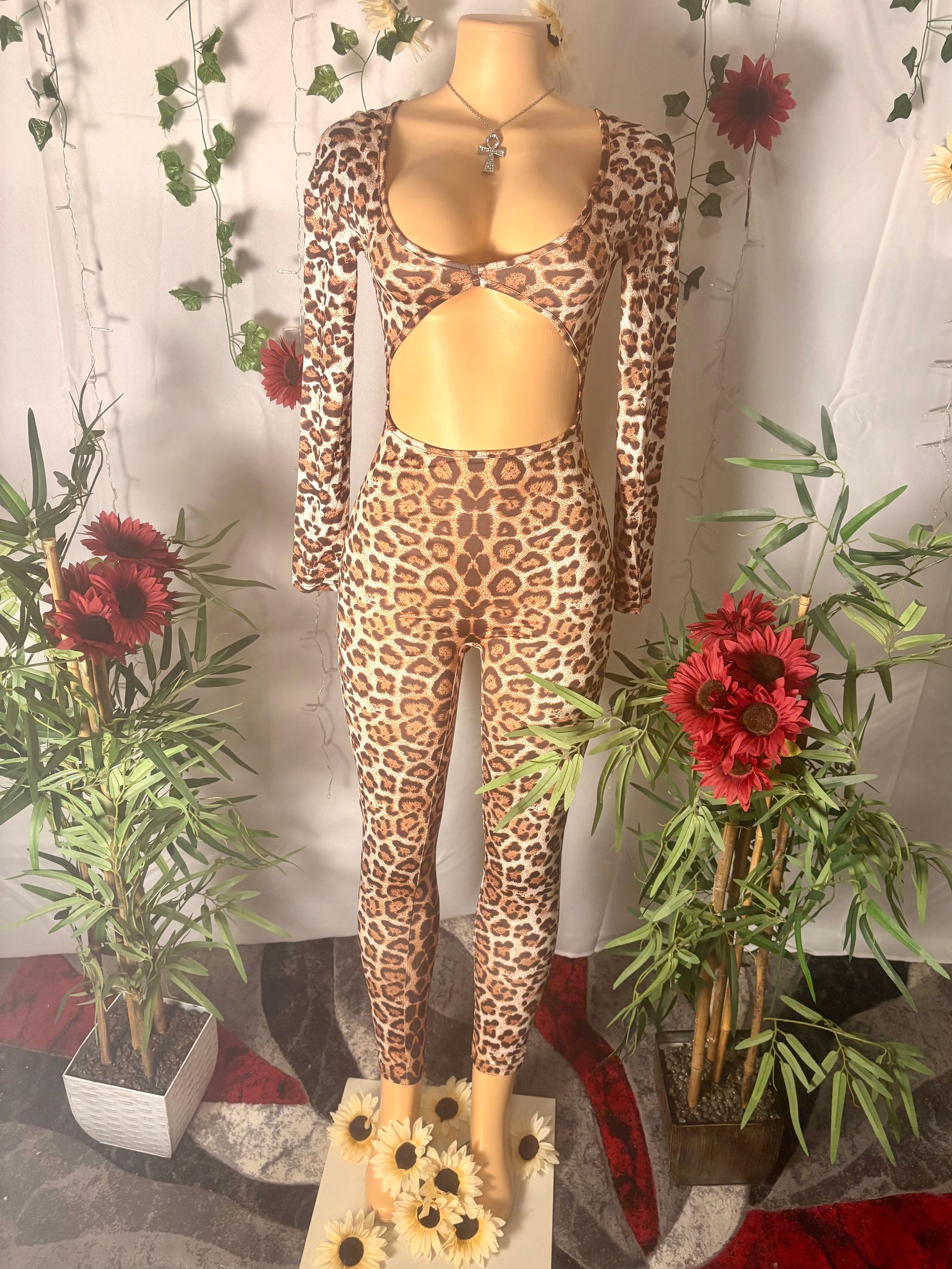 Leopard print long sleeve catsuit on a mannequin with decorative plants and flowers.