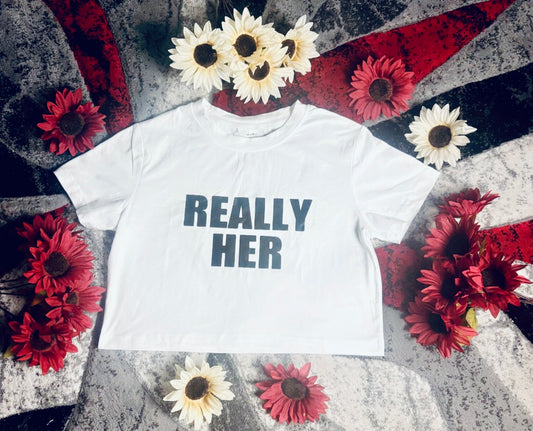 White crew neck t-shirt with 'REALLY HER' text surrounded by sunflowers on a textured surface