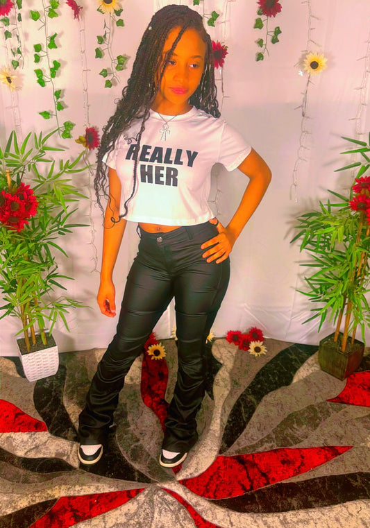 Person wearing a white crew neck t-shirt with a BOLD statement, standing in front of a decorative background with plants and flowers.