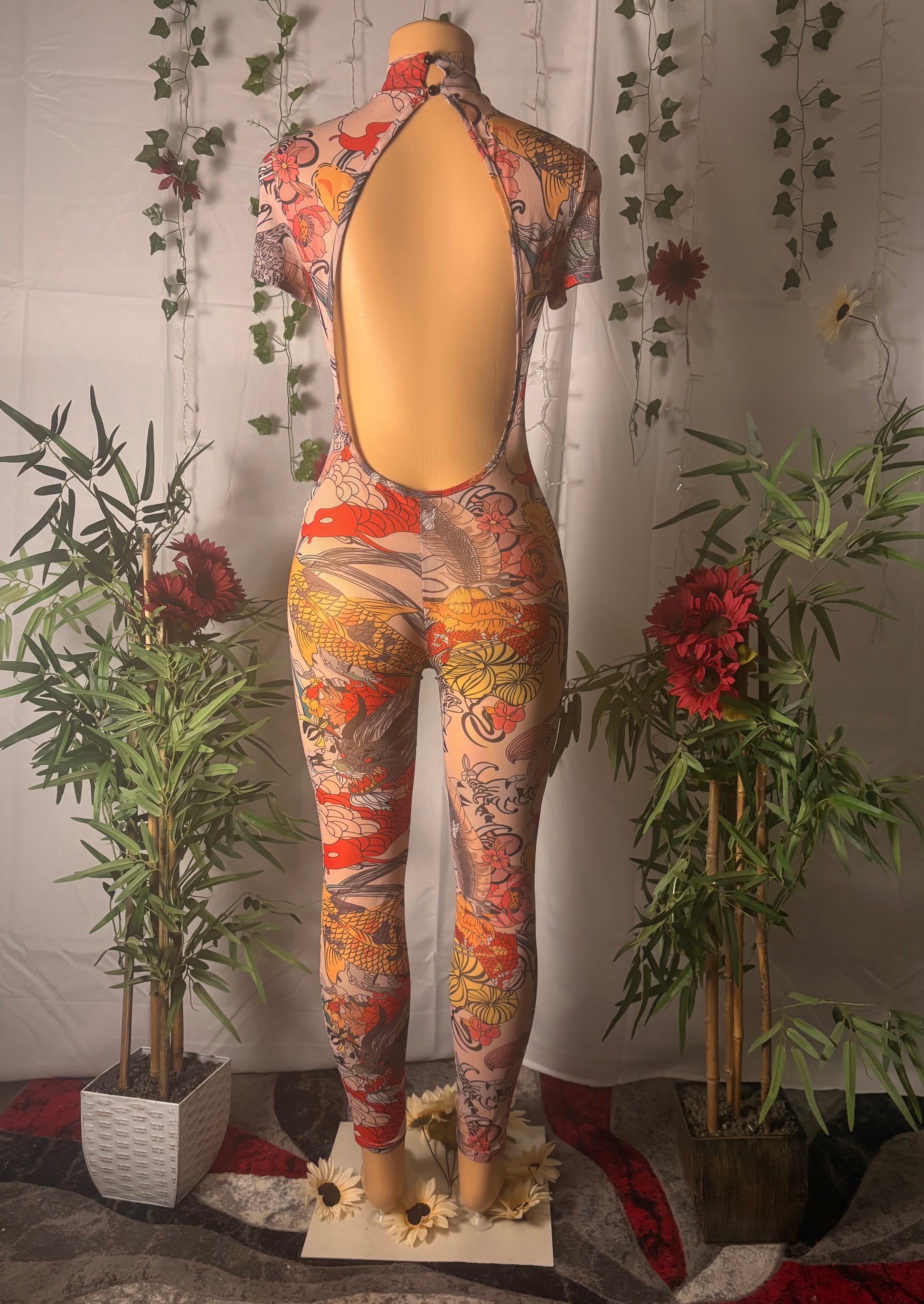 Mannequin wearing a colorful catsuit with floral patterns, surrounded by plants.