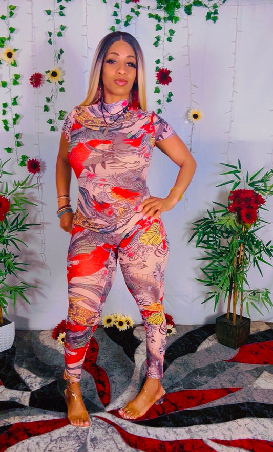Woman wearing a colorful mesh catsuit with a floral pattern in a decorated room.